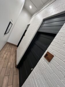 Home 6 Newly renovated restroom hallway at Pit Pros Automotive with modern finishes and clean design.